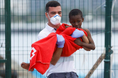 A Red Cross nurse helps a minor migrant to disembark from a Spanish coast guard vessel at the port of Arguineguin
