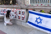 A person fixes a poster in support of Israel is posted on campus near the encampment where students are protesting in support of Palestinians