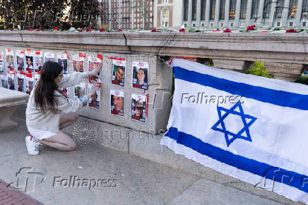 A person fixes a poster in support of Israel is posted on campus near the encampment where students are protesting in support of Palestinians