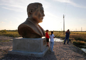 Joel Guiterrez photographs his grandchildren next to a bust of SpaceX founder Elon Musk, erected near the company's launch pad facility, in Brownsville