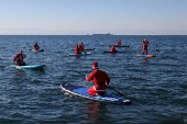 Members of the ThesSUP team wearing Santa Claus costumes paddle off the seafront of Thessaloniki