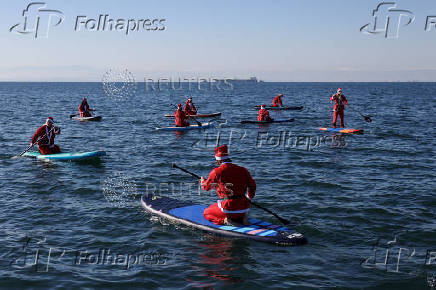 Members of the ThesSUP team wearing Santa Claus costumes paddle off the seafront of Thessaloniki