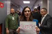 Marina Helena segura cartaz chamando adversrios ausentes de fujes antes de debate