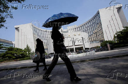 FILE PHOTO: FILE PHOTO: People walk past the headquarters of the PBOC, the central bank, in Beijing