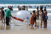 Crianas usam bolhas e colches inflveis dentro do mar, na praia Grande