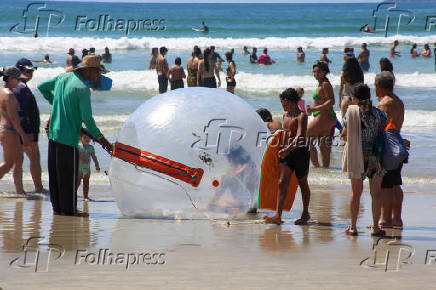 Crianas usam bolhas e colches inflveis dentro do mar, na praia Grande