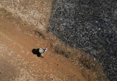 A drone view of a woman carrying a utensil filled with water after drawing it from a well on a hot day in Kasara