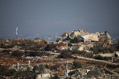 An Israeli flag hangs next to destroyed buildings in southern Lebanon, near the Israel-Lebanon border