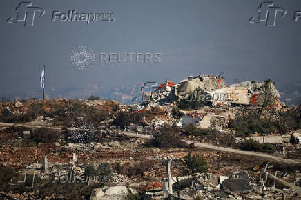 An Israeli flag hangs next to destroyed buildings in southern Lebanon, near the Israel-Lebanon border