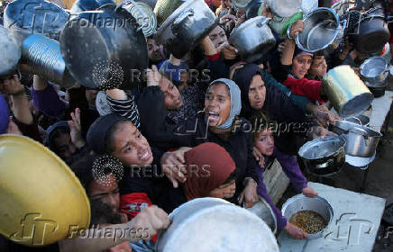 Palestinians gather to receive food cooked by a charity kitchen, in Khan Younis