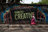 A woman walks near a wall mural in Lagos