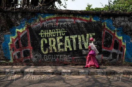 A woman walks near a wall mural in Lagos