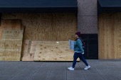 A woman walks by boarded up windows as she attends the 