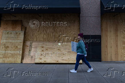 A woman walks by boarded up windows as she attends the 