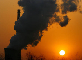 FILE PHOTO: The sun sets next to a smoke stack from a coal-burning power station in Beijing