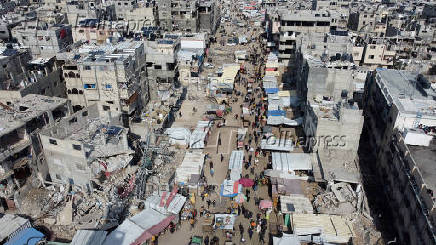 A drone view shows Palestinians walking at a street market, in Khan Younis