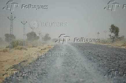 A camel crosses an under-construction road on a hot summer day in Barmer
