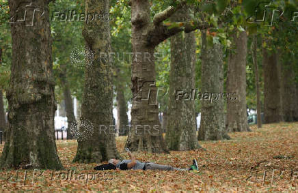 A person reads a book in St James's Park, in London