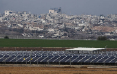 Solar panels stand on the Israeli side as buildings lie in ruin in Jabaliya in the Gaza Strip, amid the ongoing conflict between Israel and Hamas, as seen from southern Israel