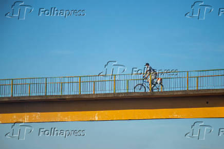 Homem de bicicleta em uma passarela sobre a rodovia Transbrasiliana