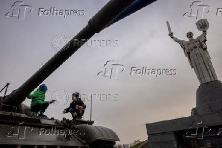 Children play on top of a tank put on display in front of the Motherland Monument in Kyiv