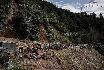 Rescue personnel work to retrieve the bodies of victims from a landslide triggered by heavy rainfall at the Tribhuwan Highway in Dhading