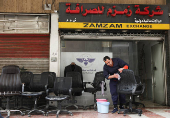 A man cleans a chair in front of a money exchange shop in Damascus