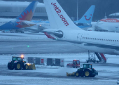 Staff use tractors to help clear snow from around aircraft after overnight snowfall caused the temporary closure of Manchester Airport in Manchester