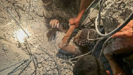 Palestinians work to rescue a child from under the rubble following an Israeli strike, amid the Israel-Hamas conflict, in Nuseirat in the central Gaza Strip