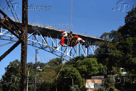 Guatemalan firefighter dressed as Santa Claus rappels down the Vacas Bridge to give toys to children, in Guatemala City