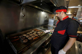 FILE PHOTO: A man cooks burgers on the grill inside a restaurant in Baghdad