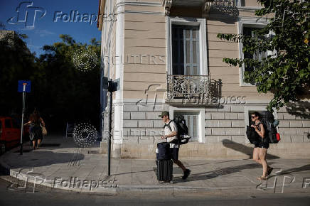 Tourists carry their luggage in the neighborhood of Koukaki, in Athens