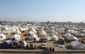 People gather near tents placed for the displaced who fled Aleppo countryside, in Tabqa