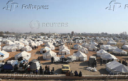 People gather near tents placed for the displaced who fled Aleppo countryside, in Tabqa