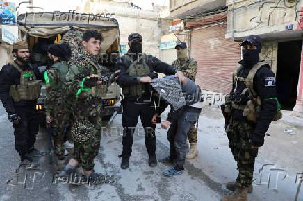 Fighters of Hayat Tahrir al-Sham (HTS) search for pro-Assad fighters and weapons in Homs