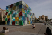 Tourists take photos next to The Cube of the Centre Pompidou Modern Art Museum, in Malaga
