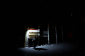 A woman walks next to a closed shop painted with a Syrian flag during curfew, in Damascus