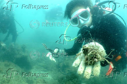 Scuba diver shows to the camera abandoned fishing nets removed from a coral reef in Phuket