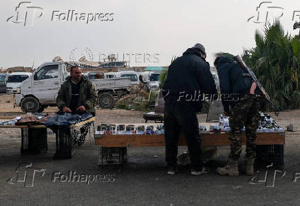 A fighter of the ruling Syrian body shops at a street market in Damascus,