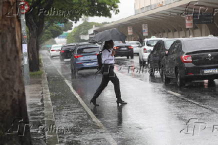 Pedestres se protegem da chuva que cai na regio do Aeroporto de Congonhas