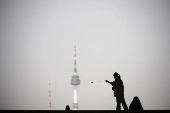 A girl plays with a yo-yo as N Seoul Tower is seen in the background at National Museum of Korea in Seoul