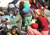 Displaced women who fled Aleppo countryside, sit with their children in Tabqa,