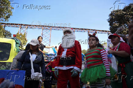 Guatemalan firefighter dressed as Santa Claus rappels down the Vacas Bridge to give toys to children, in Guatemala City