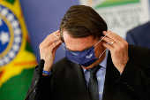 O presidente Jair Bolsonaro tenta colocar mscara durante evento