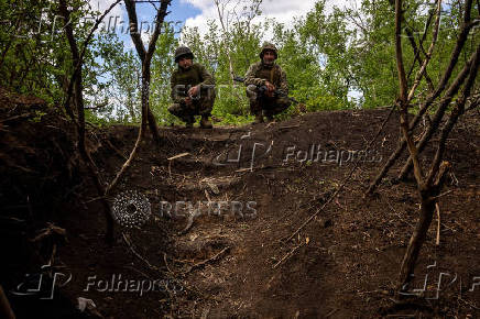 Ukrainian servicemen of the 22nd Separate Mechanised Brigade squat at an artillery position on the outskirts of Chasiv Yar