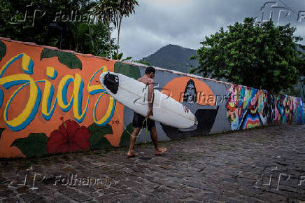 Surfista caminha pelo novo Beco da Mulher Maravilha, em Maresias (SP)
