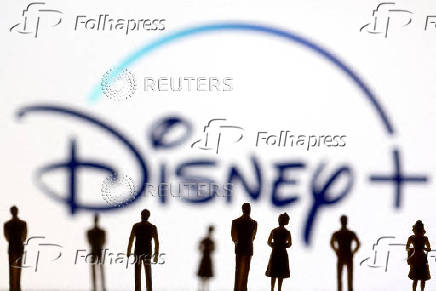 FILE PHOTO: Toy figures of people are seen in front of the displayed Disney + logo, in this illustration
