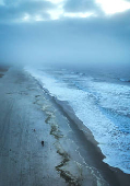 A drone view shows a woman and a dog walking along the Atlantic Ocean on Lido Beach in Hempstead, New York