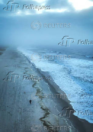 A drone view shows a woman and a dog walking along the Atlantic Ocean on Lido Beach in Hempstead, New York