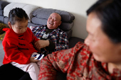 Wu rests with his granddaughter sitting on his lap after a meal at an apartment in a town bordering Beijing